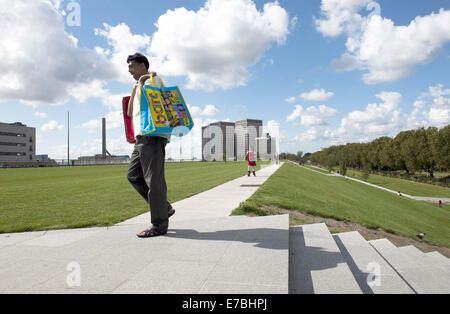 13 août 2014 - Rotterdam, Hollande méridionale, Pays-Bas, Holland - un homme avec des sacs promenades sur la le toit d'un immeuble commercial. 9 mètres au-dessous de lui est un énorme centre commercial. Dans l'arrière-plan sont des bureaux...à Rotterdam est le plus grand parc public sur un immeuble commercial en Europe. Sur 9 mètres de haut, sur le dessus à Bigshops Marconi Plaza, est un parc verdoyant avec trois jardins à thèmes..Le parc est la mesure de huit hectares et offre une vue sur la ville et le port. Il est à 800 mètres de long, 80 mètres de large et 9 mètres de haut. Ci-dessous le parc est 25 000 m2 d'espace de vente au détail.Il n'est pas seulement une zone commerçante et d'un pla Banque D'Images