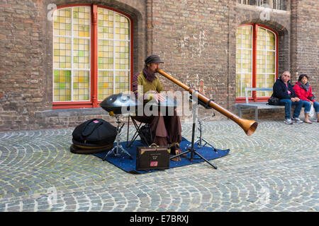 Un musicien ambulant de rue jouant un tambour d'acier et d'un didgeridoo dans la cour intérieure de la Halle à Bruges, Belgique Banque D'Images