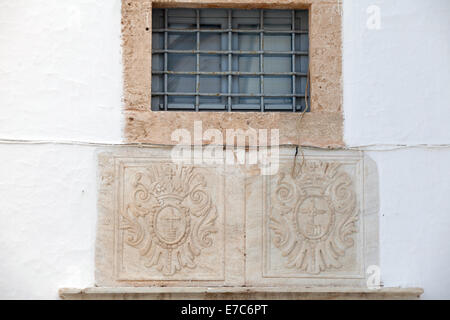 Une paire d'image miroir en pierre sculpté crêtes chrétienne situé dans un mur en dessous d'une prescription windon dans une maison à l'île d'Hydra, Grèce Banque D'Images