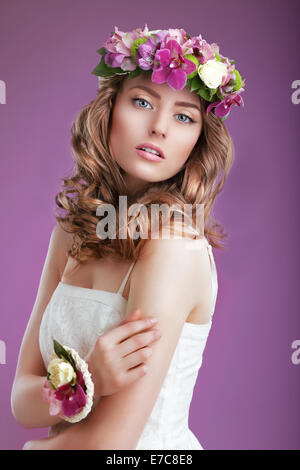 Femme exquise avec guirlande de fleurs. Dame élégante avec les cheveux crépus Banque D'Images