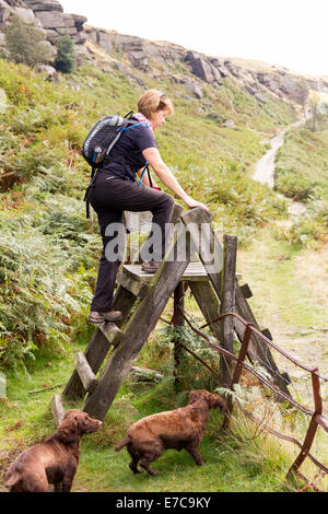 Female hiker crossing un stile sur un sentier public dans le Derbyshire Peak District Banque D'Images