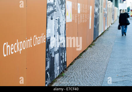 Femme marche passé un affichage en extérieur près de Checkpoint Charlie à Berlin, Allemagne Banque D'Images