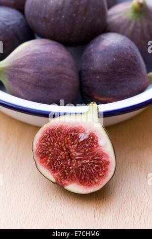 Ficus carica. Figues dans un plat en émail sur une planche de bois. Banque D'Images