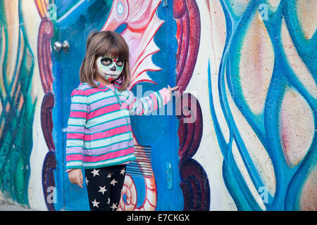 Petite fille avec visage peint pour Dia de los Muertos en face de la murale, Garfield Park, Mission District, San Francisco, Californie Banque D'Images