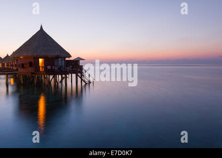 Panorama de tropical island Resort avec des bungalows sur l'eau la nuit. Les Maldives. L'Atoll d'Ari. Scenic coucher de soleil sur l'océan. Banque D'Images