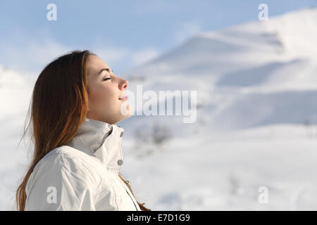 Profil d'une femme de l'explorateur de respirer l'air frais en hiver avec la montagne enneigée en arrière-plan Banque D'Images