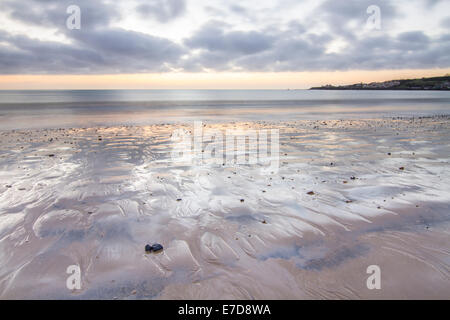 Le sable humide sur une plage tranquille à Swanage, Dorset, UK at sunrise Banque D'Images