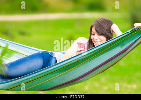 Jeune fille allongée sur un hamac avec cell phone Banque D'Images