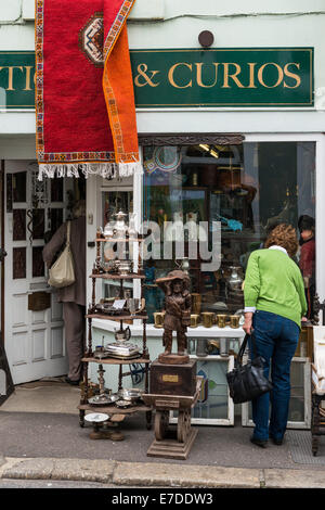 Ashburton, Devon. La vitrine d'une boutique de bibelots et antiquités à Ashburton, Devon. Une femme est à la recherche d'une fenêtre de l'écran. Banque D'Images