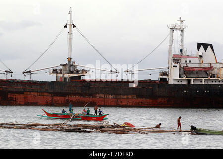 Manille, Philippines. 15 Sep, 2014. Séjour Pêcheurs sur un bateau par un navire de charge a balayé par le typhon Kalmaegi près de la baie de Manille à Manille, Philippines, le 15 septembre 2014. Le typhon Kalmaegi (nom local Luis) a fait un touché terre au nord des Philippines le dimanche après-midi et on s'attend à rester dans le pays jusqu'à mardi, l'État a déclaré l'agence météorologique. Credit : Rouelle Umali/Xinhua/Alamy Live News Banque D'Images