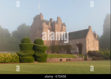 Château de Crathes du XVIe siècle, Banchory, Écosse, Royaume-Uni. Une brume matinale est suspendue au-dessus du château et de la vieille topiaire de l'if Banque D'Images