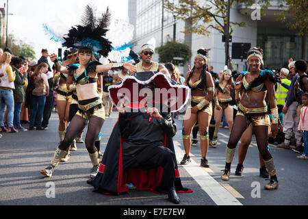 Une troupe de danse avec un prêtre comme figure principale la parade dance leur chemin passé de ville de Hackney. Banque D'Images