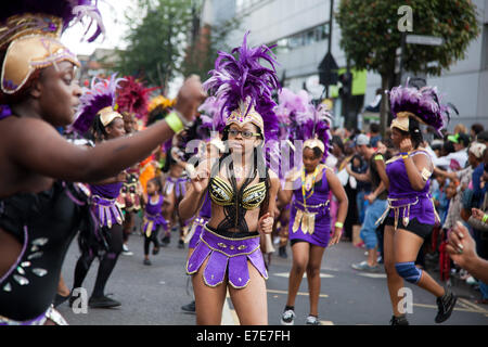 Les femmes danseurs vêtus de pourpre font leur chemin passé de ville de Hackney sous les applaudissements de la foule. Banque D'Images