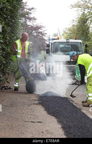 Jeter des ouvriers à un sentier en asphalte après l'installation de nouveaux câbles à fibre optique pour la haute vitesse à large bande Banque D'Images