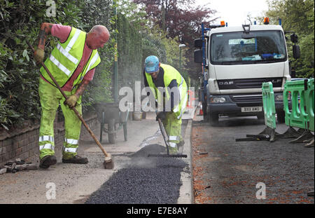 Jeter des ouvriers à un sentier en asphalte après l'installation de nouveaux câbles à fibre optique pour la haute vitesse à large bande Banque D'Images