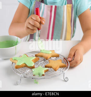 Girl decorating cookies en forme d'étoile avec du glaçage, 5 ans Banque D'Images