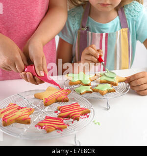 Girl decorating cookies en forme d'étoile avec du glaçage Banque D'Images