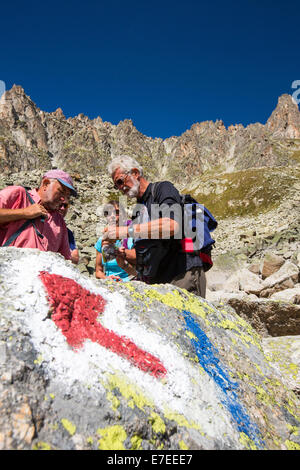 Un pointeur sur le rocher dans le Val d'Arpette dans les alpes suisses sur le Tour du Mont Blanc, avec les randonneurs faisant le tour. Banque D'Images