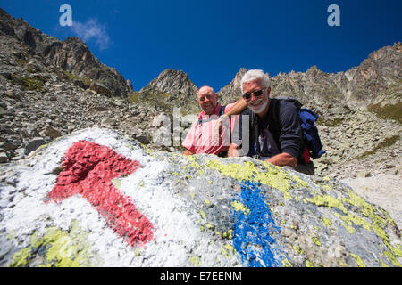 Un pointeur sur le rocher dans le Val d'Arpette dans les alpes suisses sur le Tour du Mont Blanc, avec les randonneurs faisant le tour. Banque D'Images