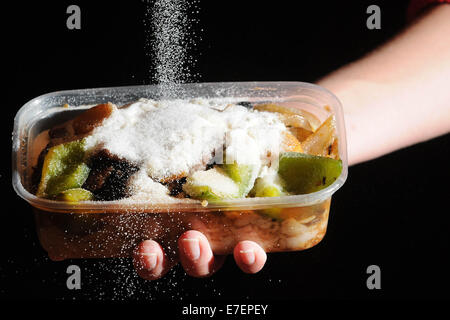 Une femme verse du sel sur un repas à emporter malsaine. Banque D'Images