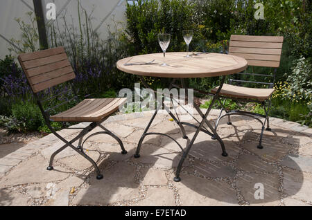 Petit jardin circulaire jardin cercle patio fait de pavage en pierre de Purbeck avec table en bois et chaises Royaume-Uni Banque D'Images