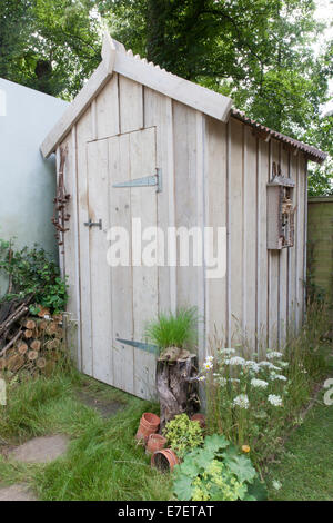 Jardin - Jardin Hérisson - vue de l'abri de jardin avec bugs insectes hôtel sur le mur et pile de billots pour la faune Banque D'Images