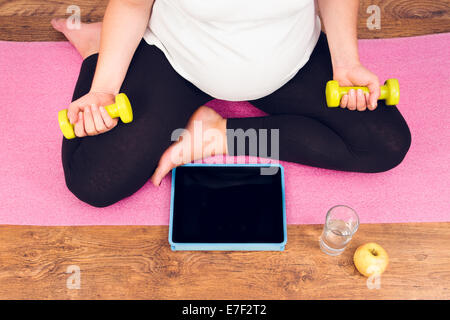 Femme enceinte active avec l'entraînement avec haltères cours vidéo Banque D'Images