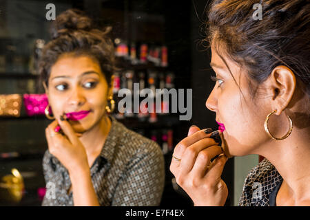 Young woman applying lipstick, dans une boutique, Mumbai, Maharashtra, Inde Banque D'Images