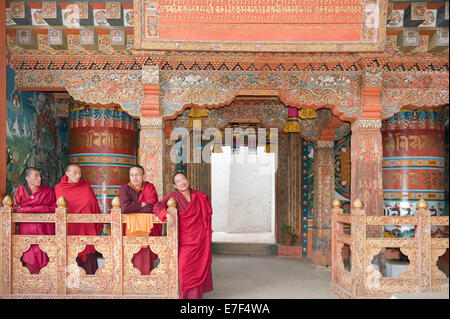 Quatre moines en robes rouges, mur en bois orné, Bouddhiste Tango Goemba monastère près de Thimphu, Royaume du Bhoutan Banque D'Images