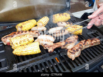 La cuisson des aliments sur un barbecue à gaz, London, y compris les saucisses de porc de la Giggly Pig Banque D'Images