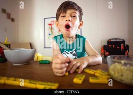 Mixed Race boy à jouer avec des dominos à table de cuisine Banque D'Images