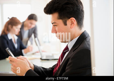 Businessman using cell phone in office Banque D'Images