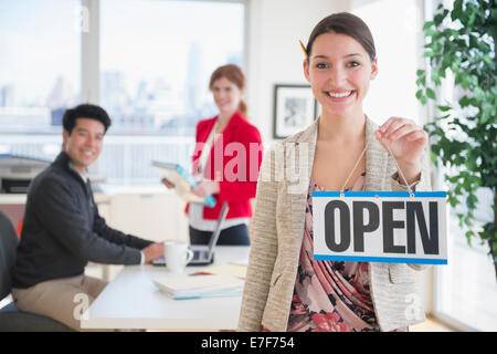 Businesswoman holding Open sign in office Banque D'Images