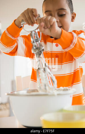 Mixed Race boy baking in kitchen Banque D'Images