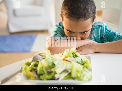 Mixed Race boy refuse de manger de la salade Banque D'Images