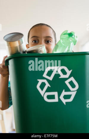 Mixed Race boy carrying recycling Banque D'Images