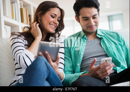 Couple à l'aide de la technologie ensemble sur canapé Banque D'Images