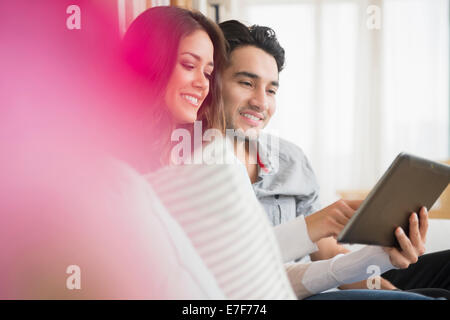 Couple using tablet computer on sofa Banque D'Images