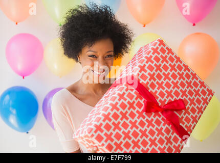 African American Woman holding wrapped gift at Birthday party Banque D'Images