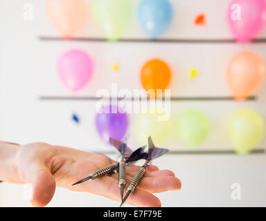 African American Woman holding fléchettes par mur de ballons Banque D'Images