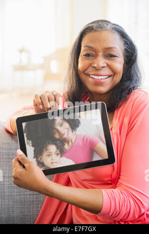 Mixed Race woman using tablet computer on sofa Banque D'Images