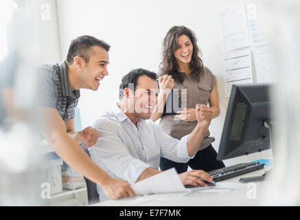 Hispanic business people cheering together in office Banque D'Images