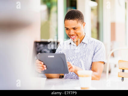 African American man using tablet computer at sidewalk cafe Banque D'Images