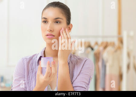 Caucasian woman applying moisturizer à face Banque D'Images