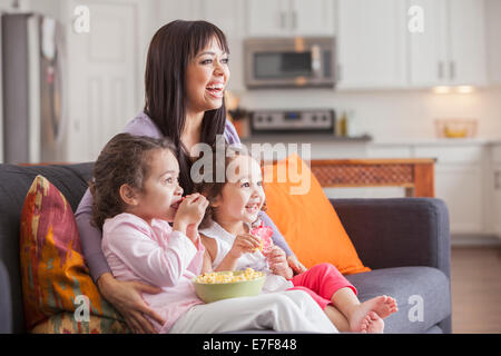 La mère et les filles à regarder la télévision sur le canapé Banque D'Images