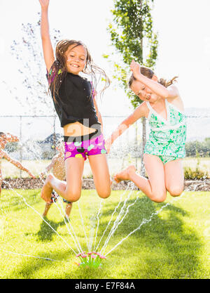 Caucasian girls playing in backyard sprinkleur Banque D'Images