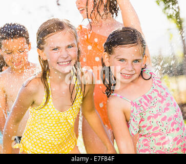 Caucasian Children playing in backyard sprinkleur Banque D'Images