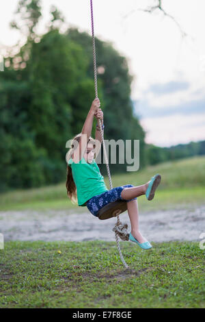 Caucasian girl playing on rope swing Banque D'Images