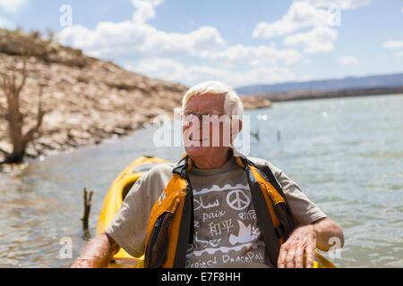 Older Caucasian man l'aviron sur le lac Banque D'Images