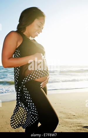 Pregnant woman holding her belly on beach Banque D'Images